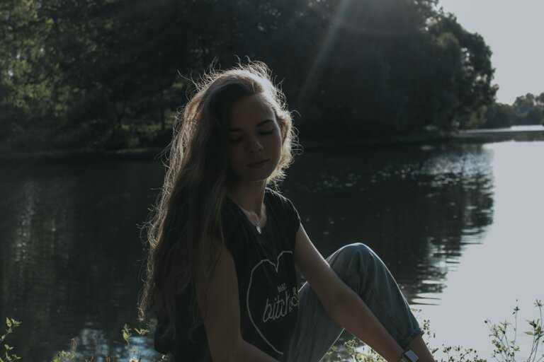 woman in black and white crew neck t-shirt standing near lake during daytime