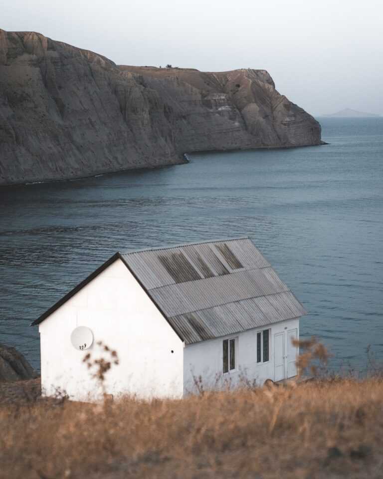 white and brown wooden house near body of water during daytime
