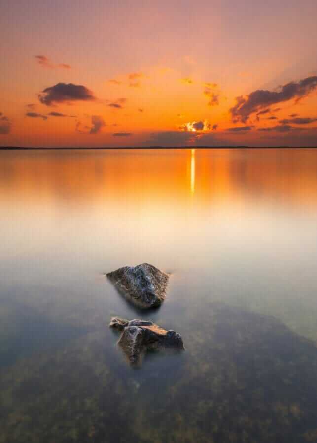 calm water under orange sky during sunset
