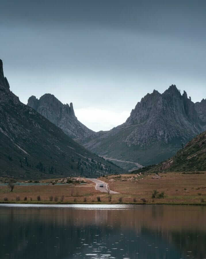 lake near mountain under white sky during daytime