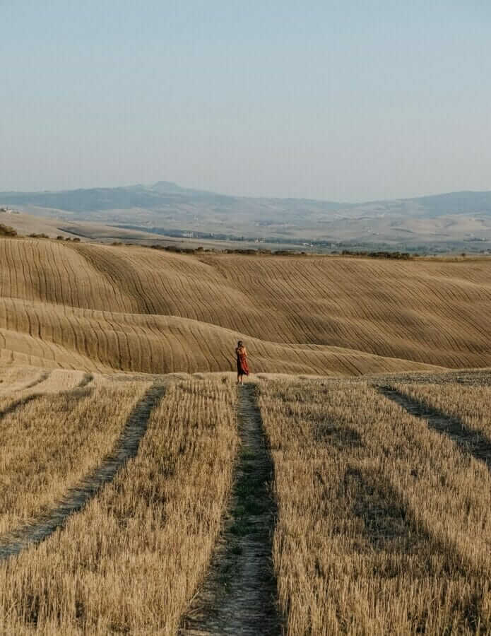 person in red jacket walking on brown field during daytime