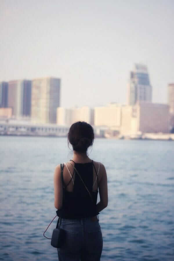 woman in black tank top standing near body of water during daytime