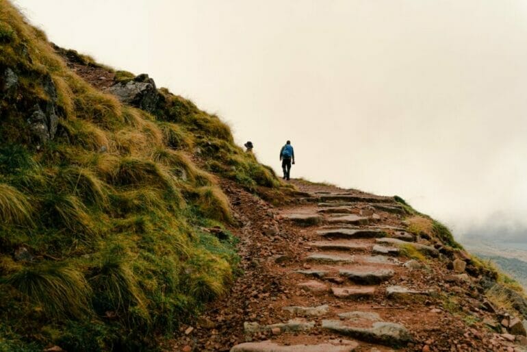 a person walking on a path in a foggy mountain