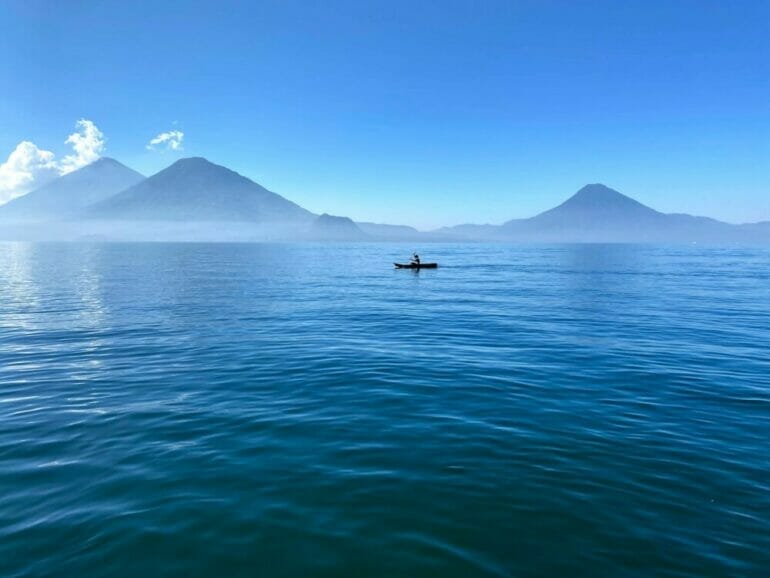 person in boat on sea near mountain during daytime