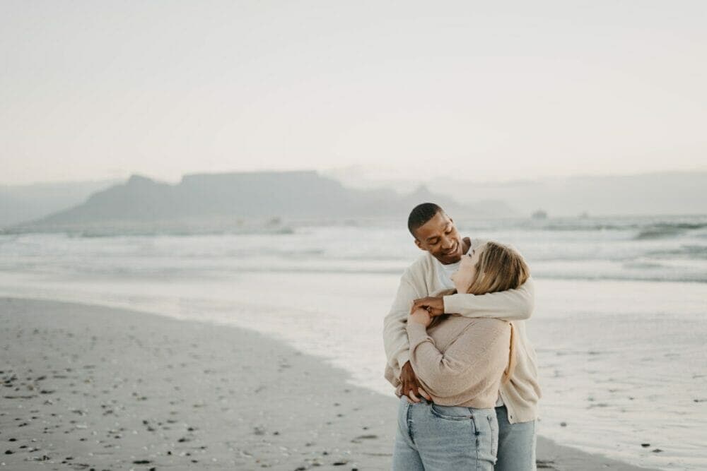 a man and a woman hugging on the beach