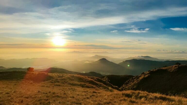 the sun is setting over the mountains in the distance