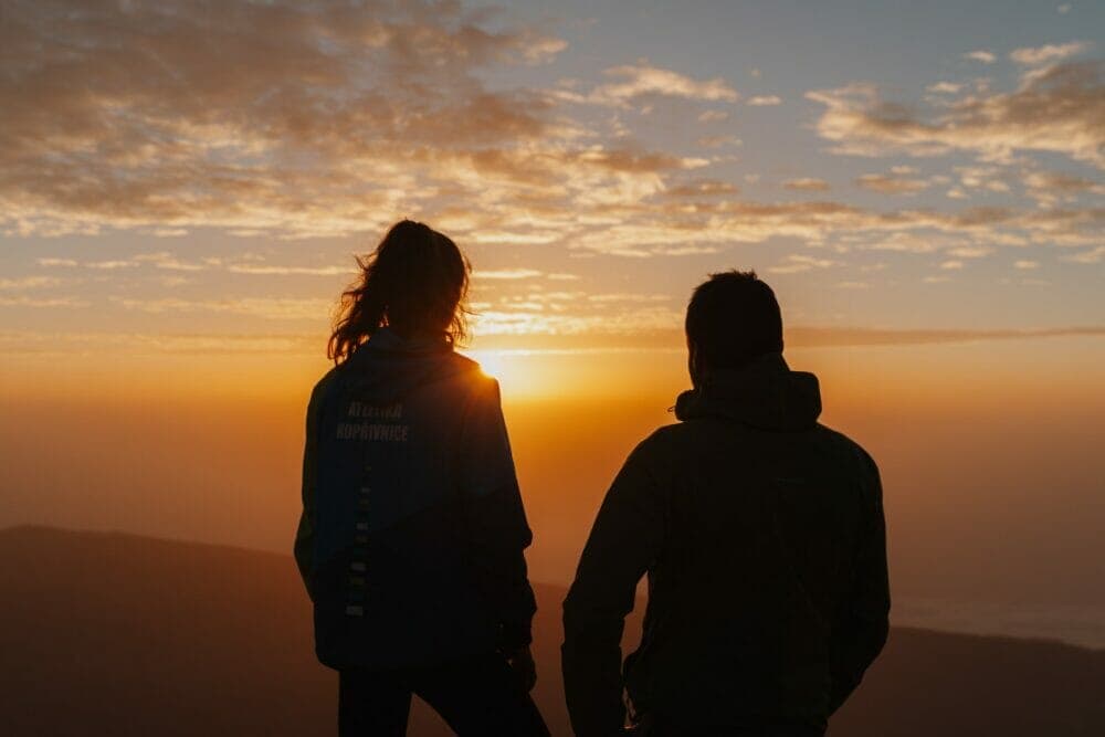 silhouette of man and woman standing during sunset