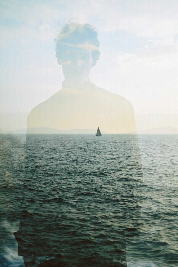Silhouette of Man with Sailboat behind