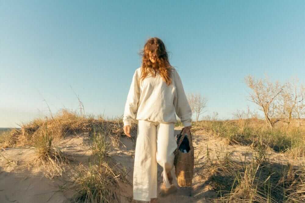 a woman walking a dog on a sandy beach