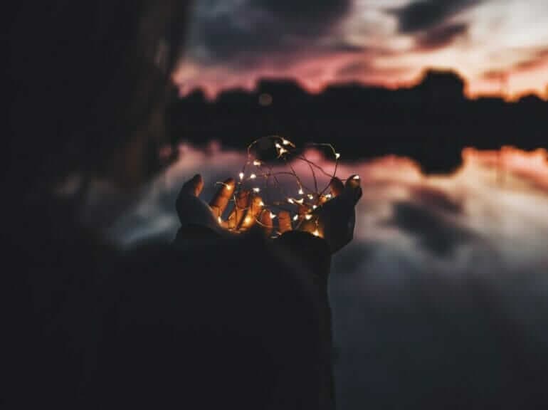 La formule magique pour plus de vie, plus de bonheur et plus d'énergie person holding turned on string lights during nighttime