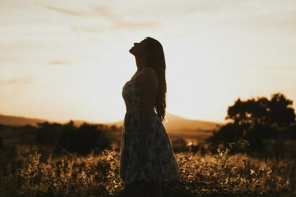 woman wearing floral dress standing on brown grassland