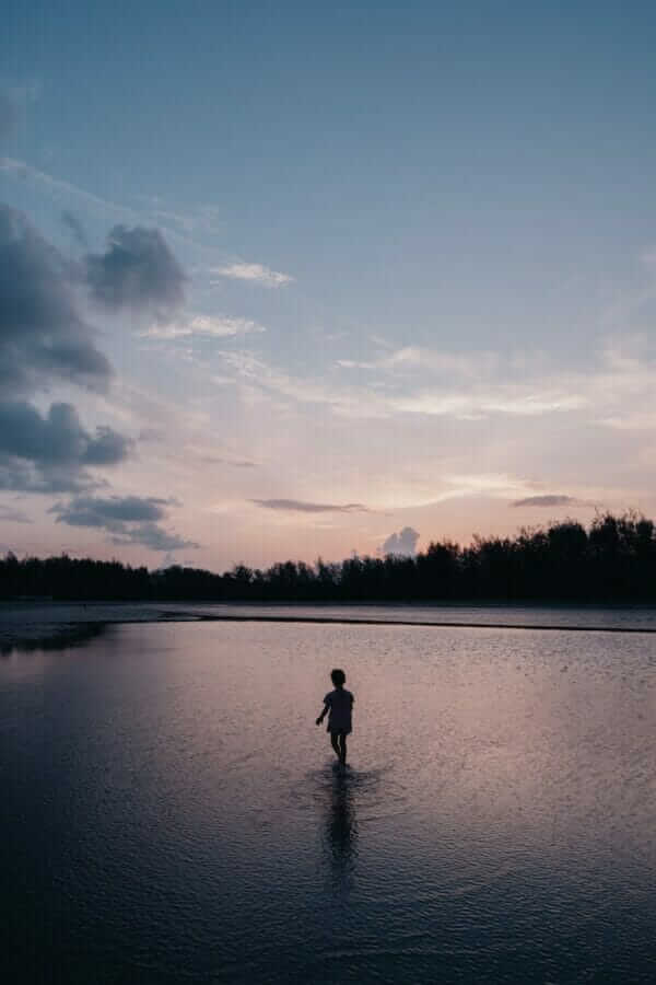 a person wading in a body of water at sunset