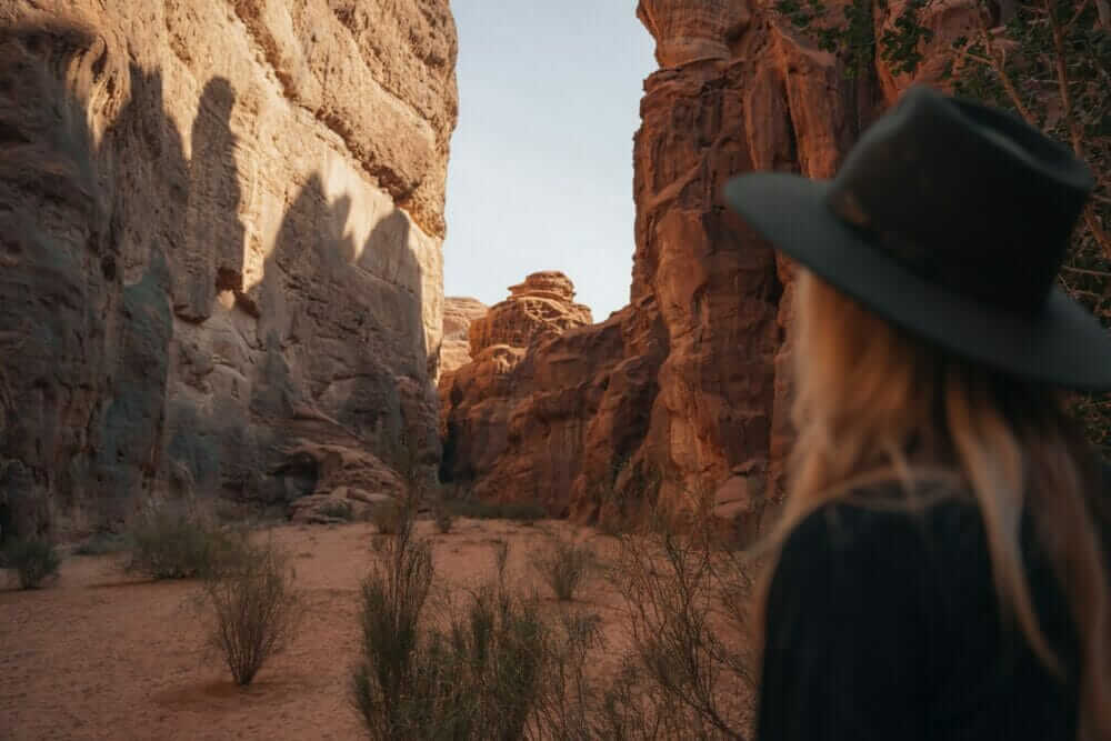 a woman wearing a hat standing in a canyon