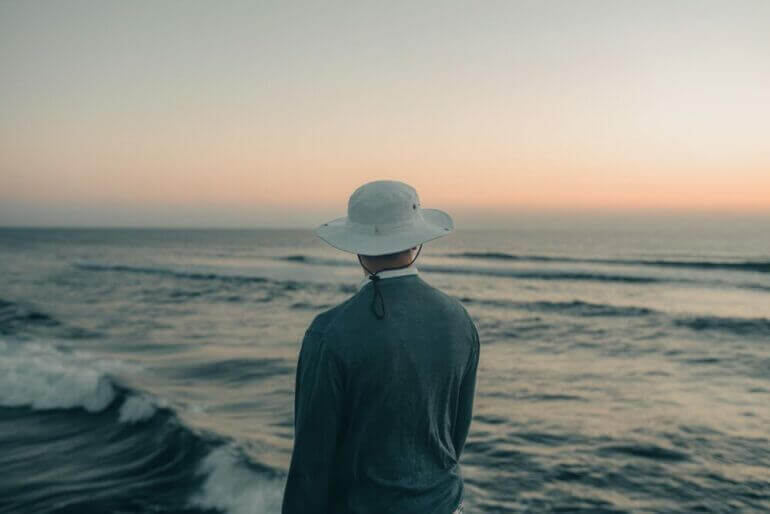 a man standing on a beach looking out at the ocean