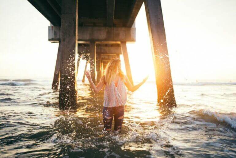 woman stading in water under a dock during golden time
