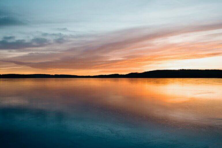 calm body of water near mountain during golden hour