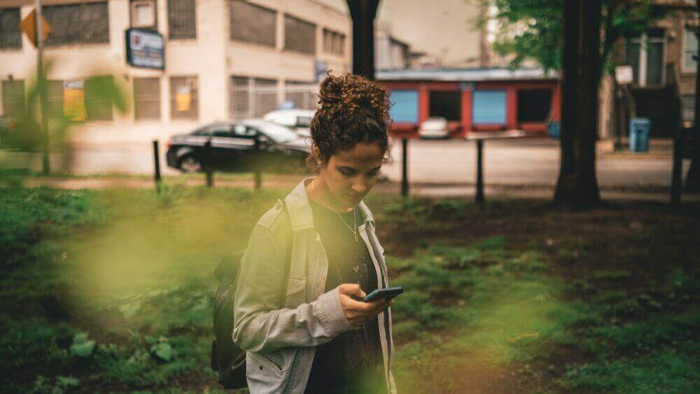 a woman standing in the grass looking at her cell phone