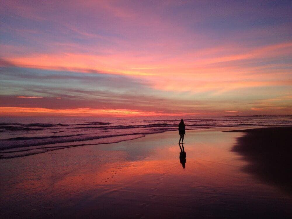 person walking on beach during sunset