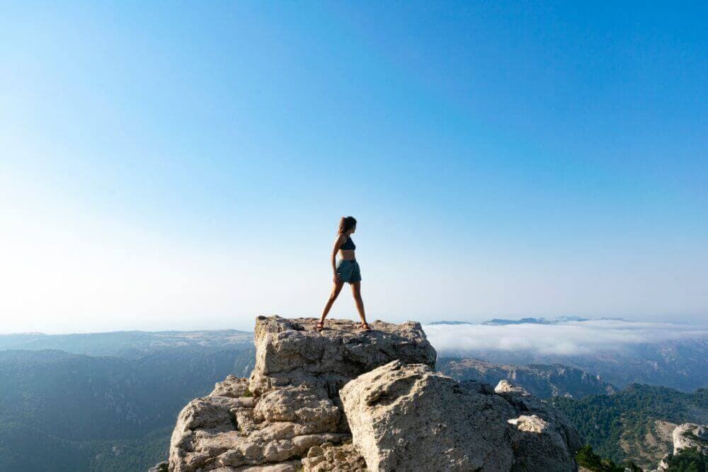 woman in black tank top standing on rock formation during daytime