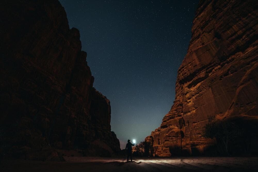 a person standing in the middle of a canyon at night