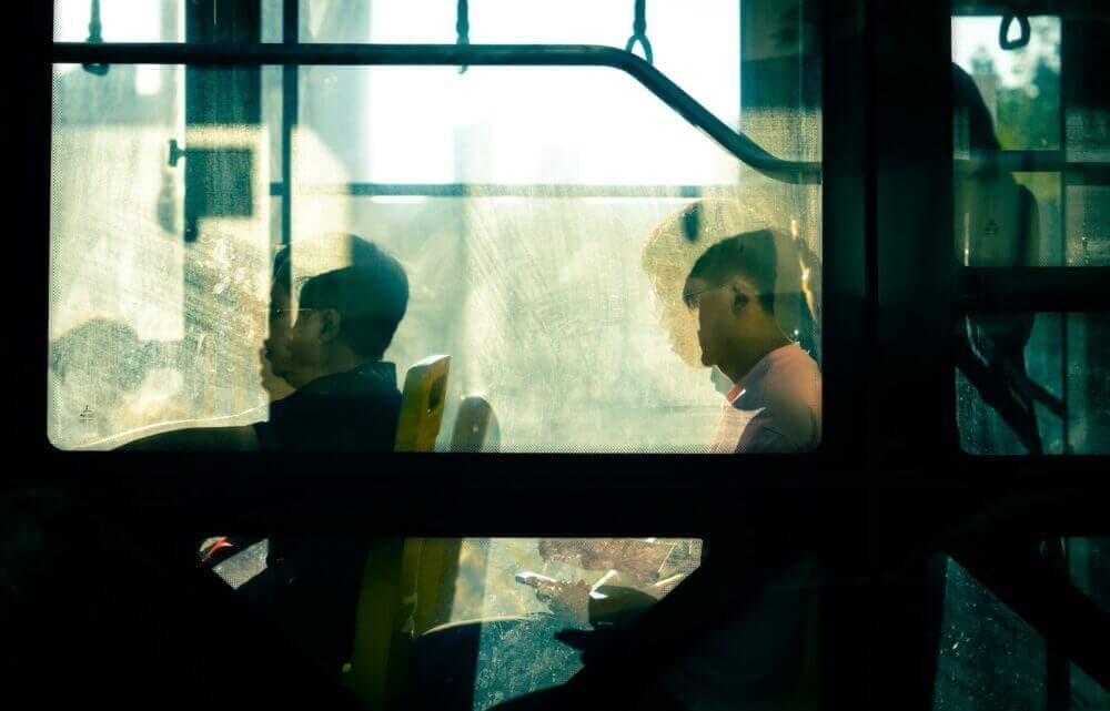 two people sitting on a bus looking out the window