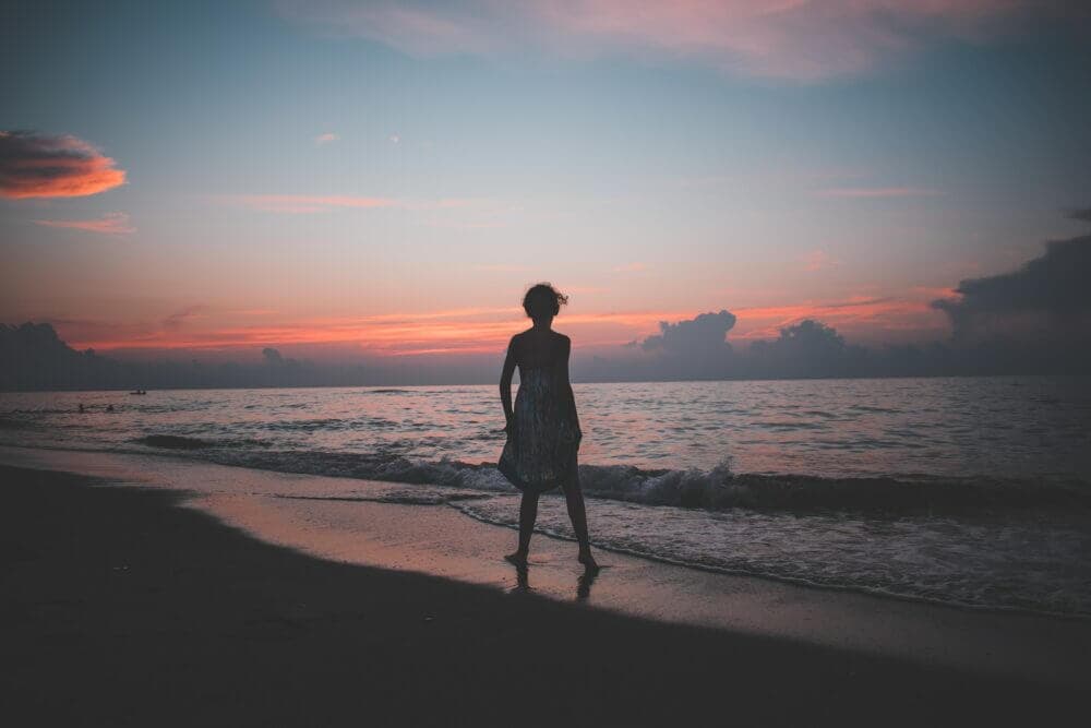 woman standing on the seashore during golden hour