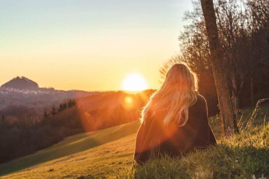 woman sitting on green grass looking at the sun
