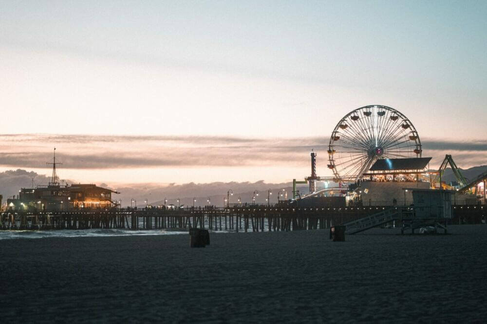 a ferris wheel sitting next to a pier at dusk