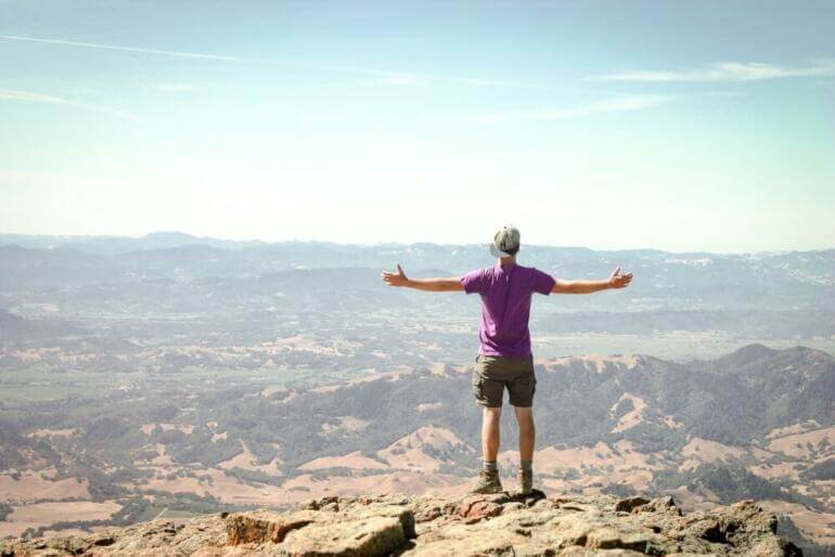 man stand on brown mountain under blue sky