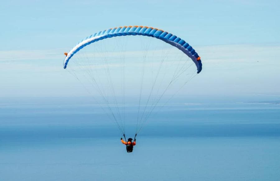 person parachuting under blue sky
