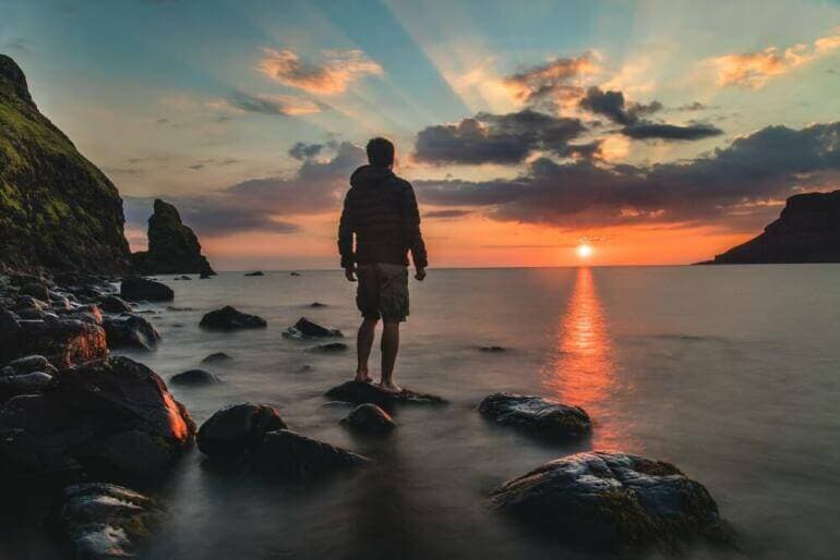 Ni le succès ni l’échec ne sont définitifs man standing on stone looking at sunset
