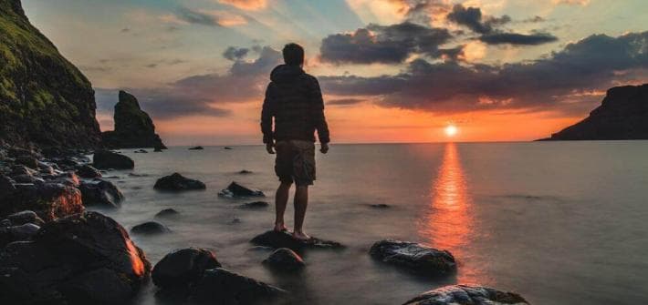 Ni le succès ni l’échec ne sont définitifs man standing on stone looking at sunset