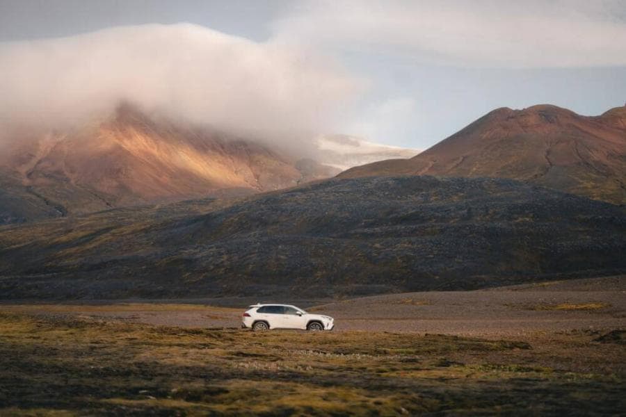a car is parked in a field with mountains in the background