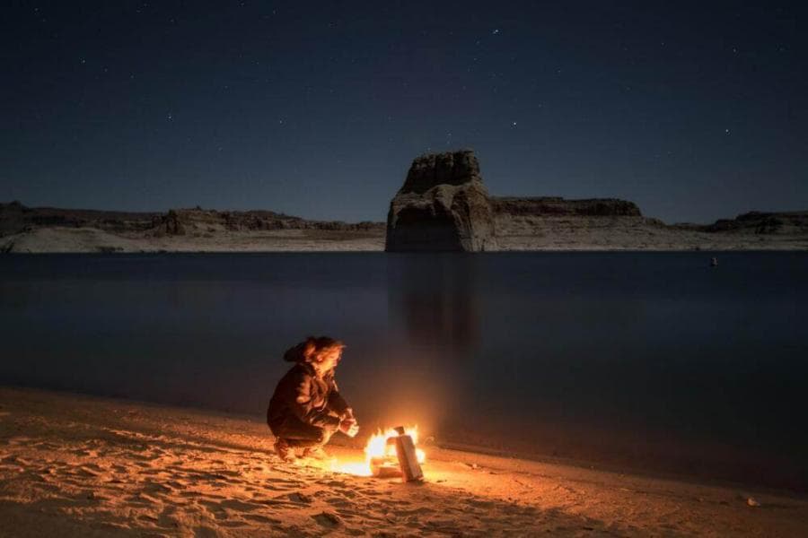 person sitting beside bonfire on seashore