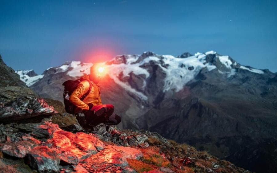 a man sitting on top of a mountain next to a light
