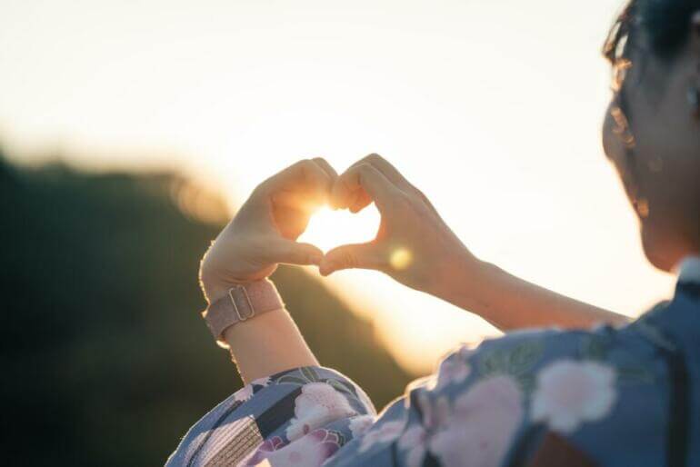 a woman making a heart shape with her hands