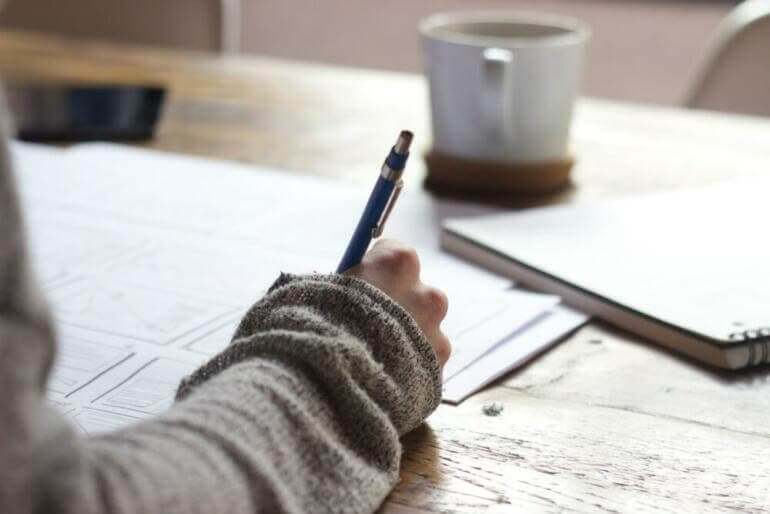 Se connaître pour avoir confiance : le secret de l'épanouissement personnel person writing on brown wooden table near white ceramic mug