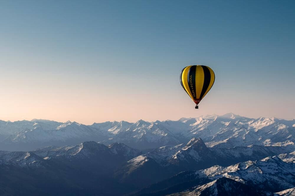 yellow and blue hot air balloon flying over the mountains during daytime