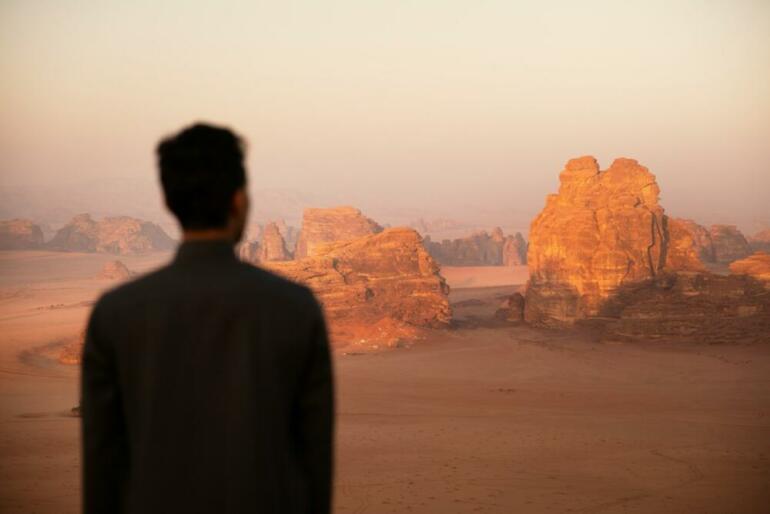 a man standing in front of a desert landscape