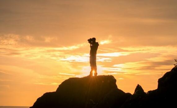 a person standing on top of a rock near the ocean
