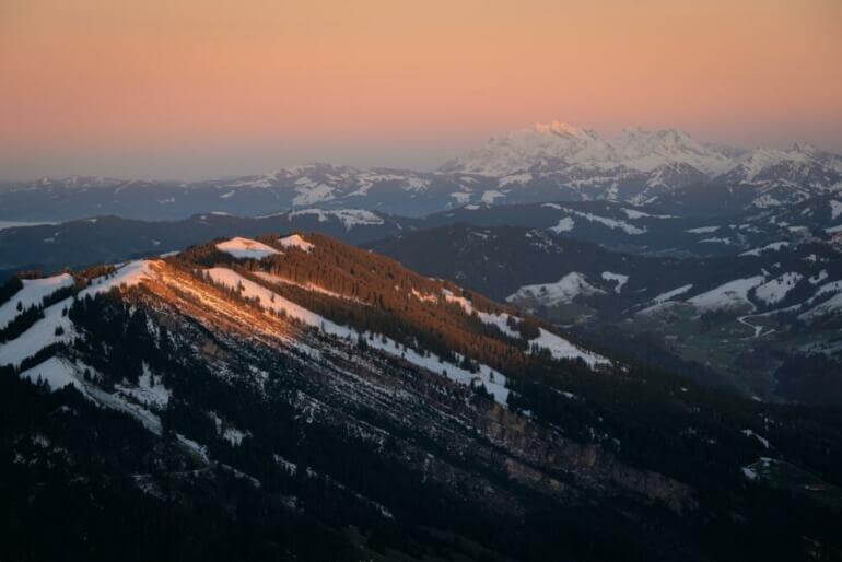 a view of a snowy mountain range at sunset