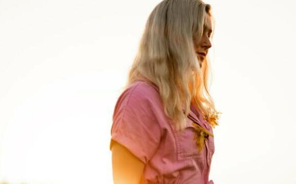 a woman in a pink jumpsuit standing in a field
