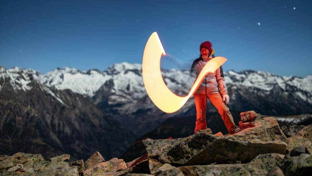 a woman standing on top of a mountain holding a frisbee
