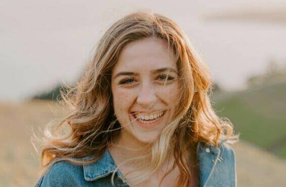 smiling woman sitting on grass during daytime