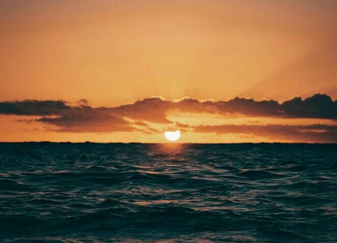 the sun is setting over the ocean