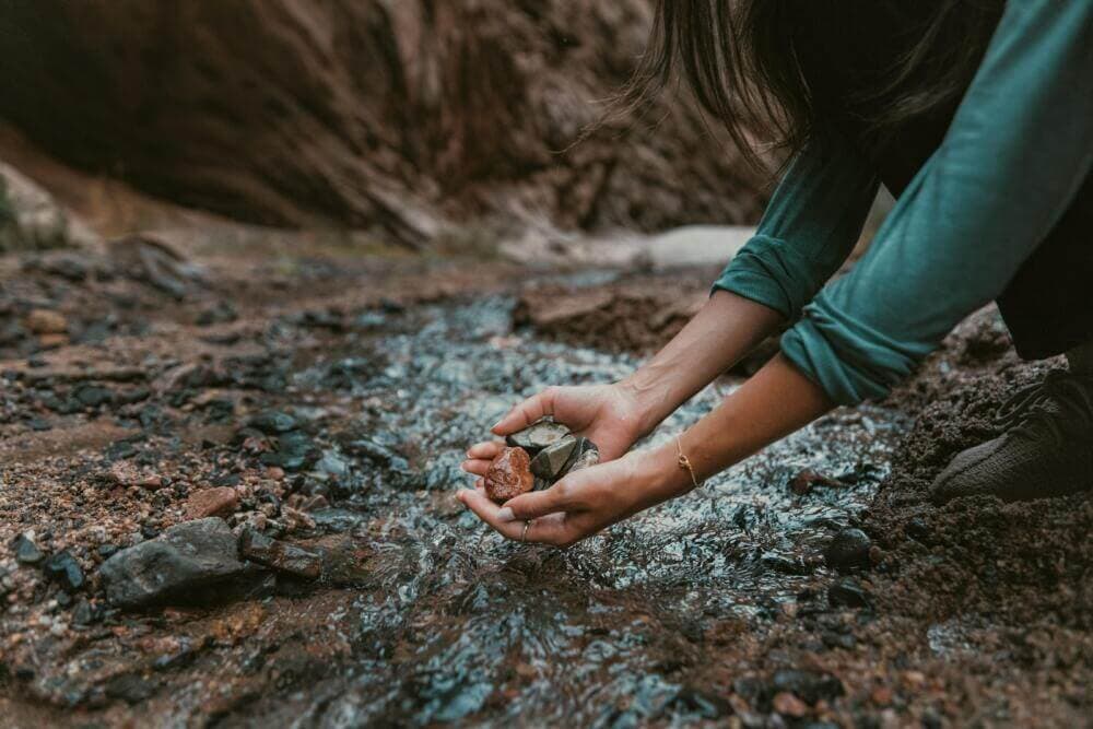 a person kneeling down and holding a rock in their hands