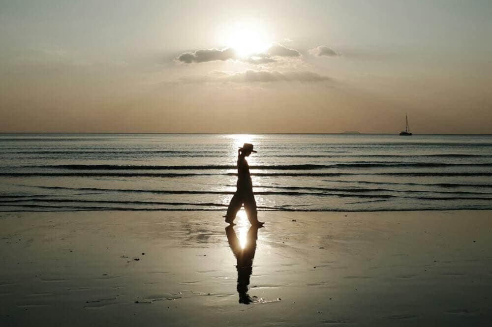 A person walking on the beach at sunset