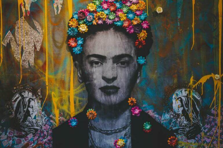 Creative artwork with Frida Kahlo painting decorated with colorful floral headband on graffiti wall