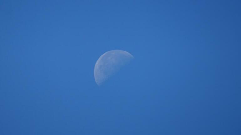 a half moon in a clear blue sky