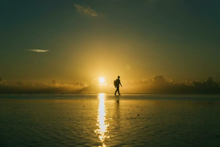 6 idées reçues sur la Manifestation Silhouette of a lone hiker walking on a beach during a picturesque sunset.